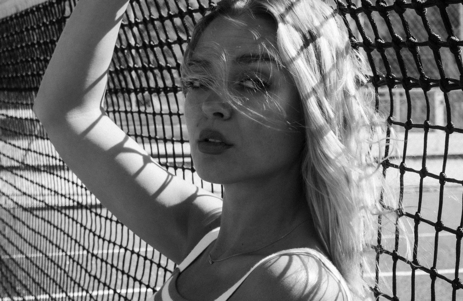 Portrait noir et blanc derrière un filet de tennis